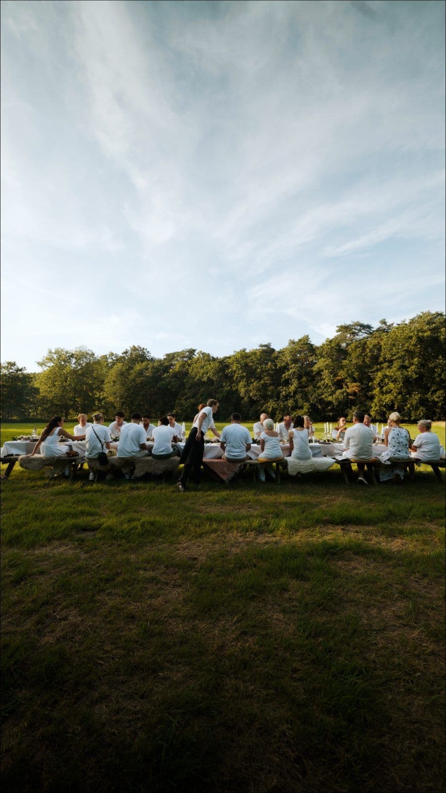Lange gedekte tafel in een veld bij avondlicht