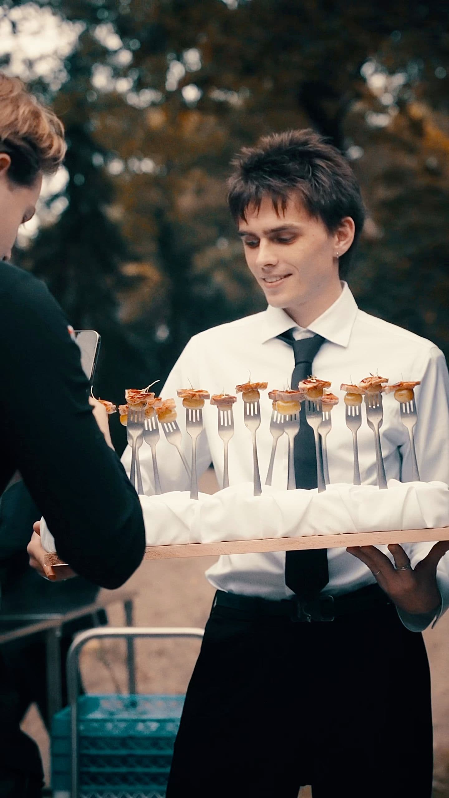 Een ober serveert spiesjes op een dienblad tijdens een borrel buiten