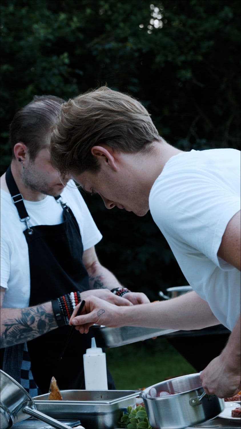 Twee koks werken geconcentreerd aan de mise-en-place op locatie