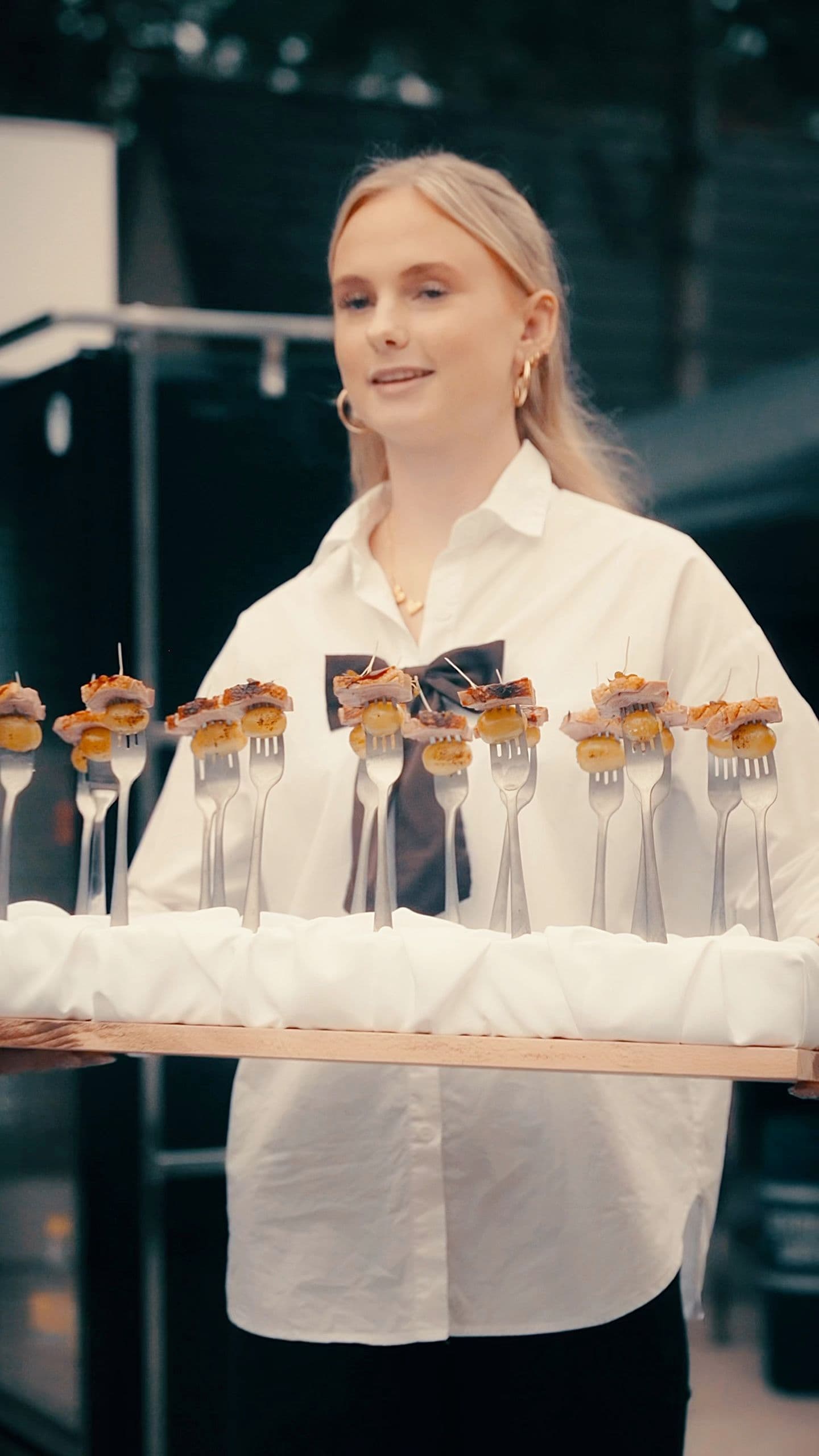 Serveerster met een plank vol hapjes op vorkjes tijdens de opening van het vakantiepark